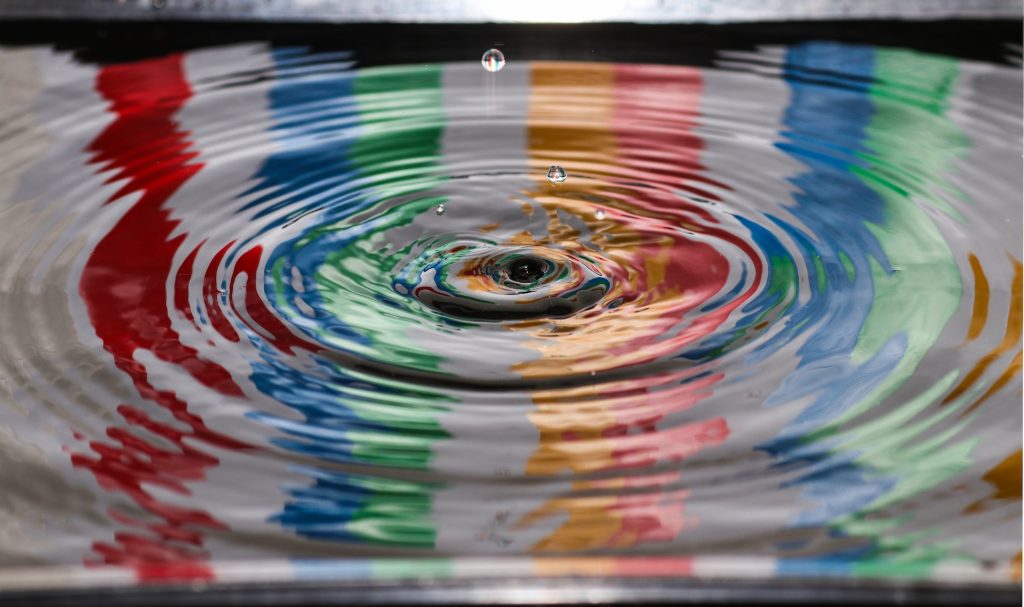 The impact of a droplet on water with colours. Illustrating the impact of Curiosity on personal development and transformation. Photo by Jordan McDonald on Unsplash.